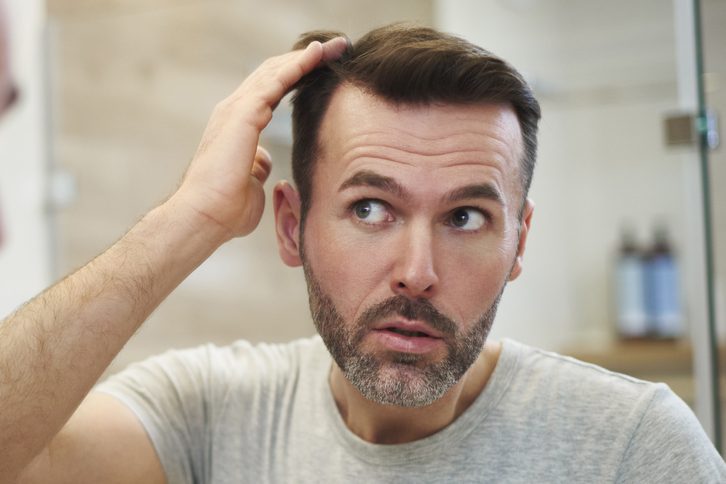 man checking his hair in a mirror