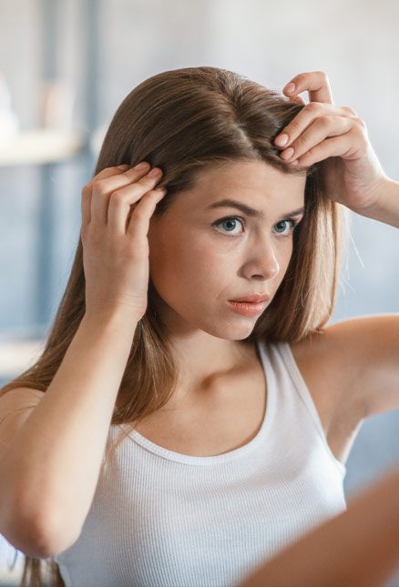 girl separating her hair in the mirror